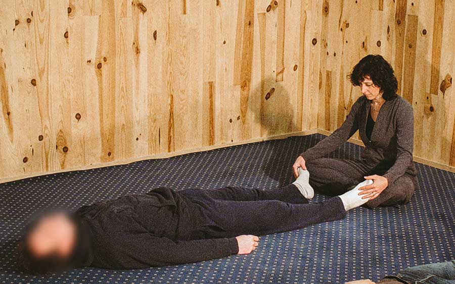 Catherine Legrand assise tenant les chevilles d’une personne allongée lors d’une séance de psychanalyse corporelle