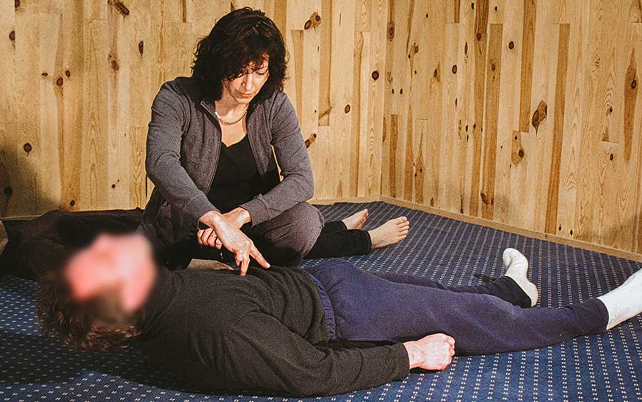 Catherine Legrand assise au sol observant une personne allongée pendant une séance de psychanalyse corporelle